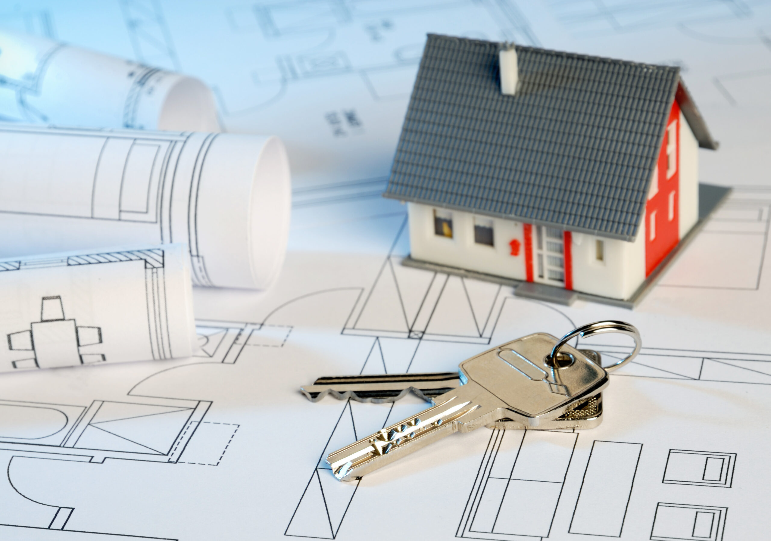 Ein Modellhaus sowie ein Schlüssel liegen auf Bauplänen. Die VE-Bau GmbH ist Ihr Partner für schlüsselfertiges Bauen in Schleswig-Holstein.