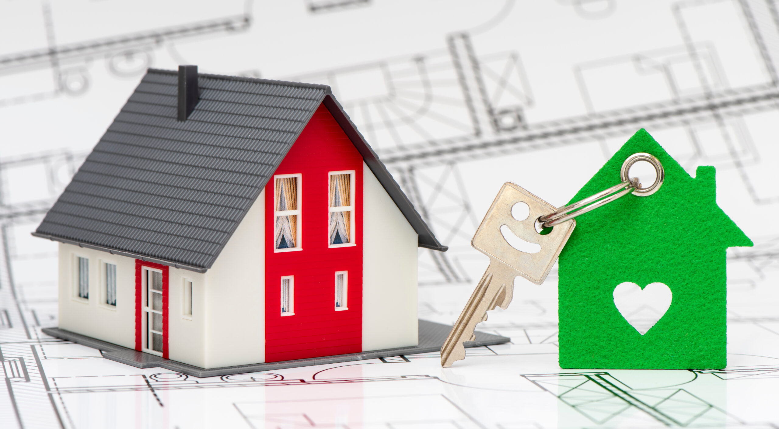 Wohnbau gegen Wohnungsnot Ein Modellhaus und ein Schlüssel mit einem grünen Anhänger symbolisieren die Leistung für schlüsselfertiges Bauen eines Bauunternehmens aus Schleswig-Holstein.