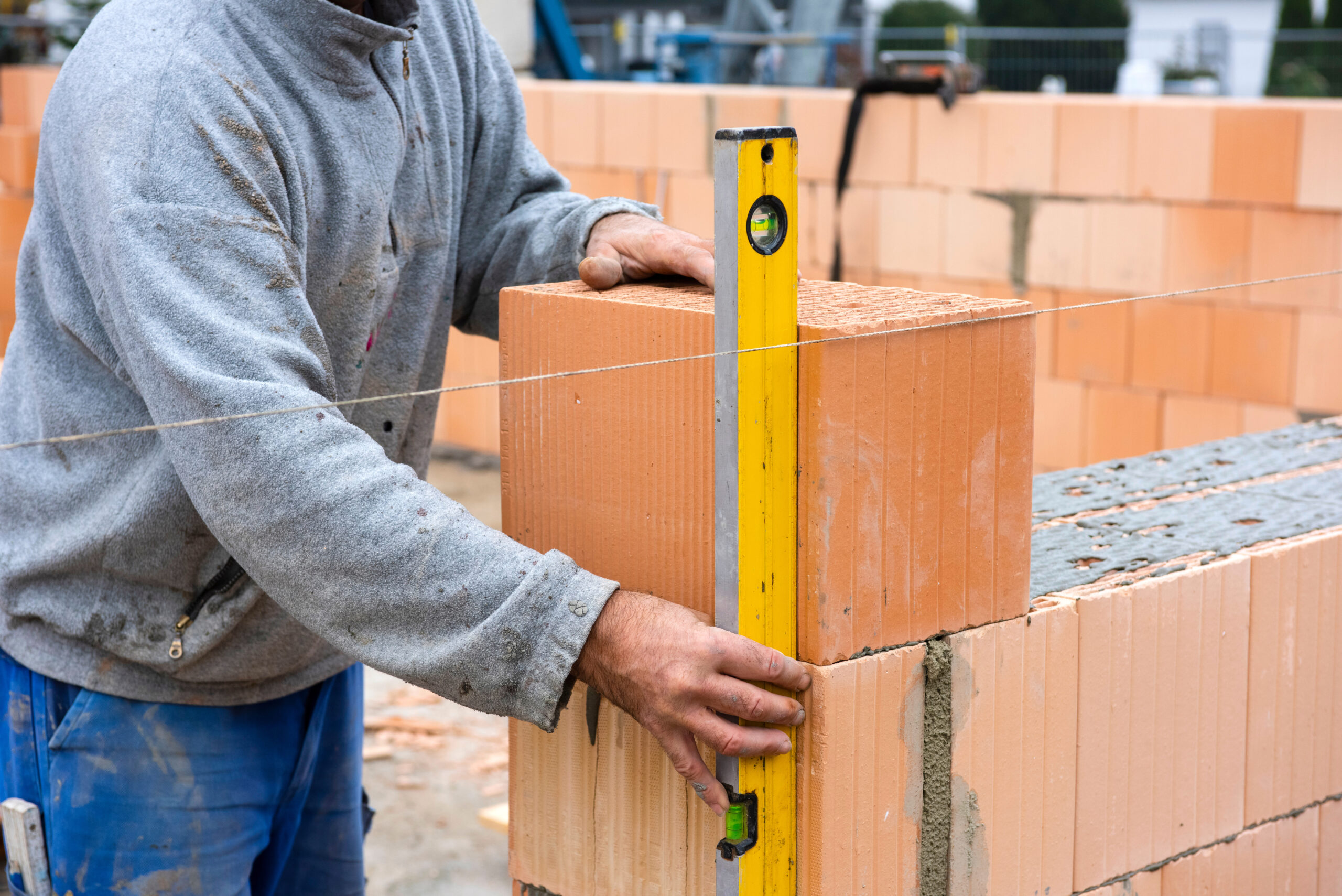 Ein Wohnhaus wird mit Ziegel errichtet Ein Maurer eines Bauunternehmens aus Schleswig-Holstein führt Mauerwerksarbeiten mit einer Wasserwaage aus.